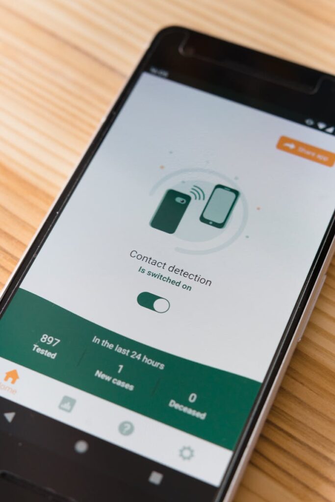 Vertical shot of a smartphone displaying a contact detection app on a wooden table.